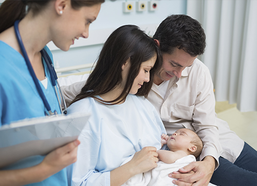 Padres sosteniendo a su hijo recién nacido junto a una enfermera