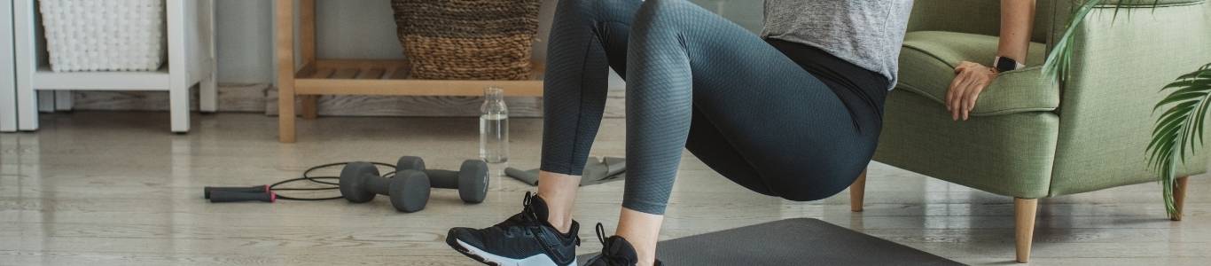 como-retomar-la-actividad-fisica mujer haciendo ejercicio en su casa