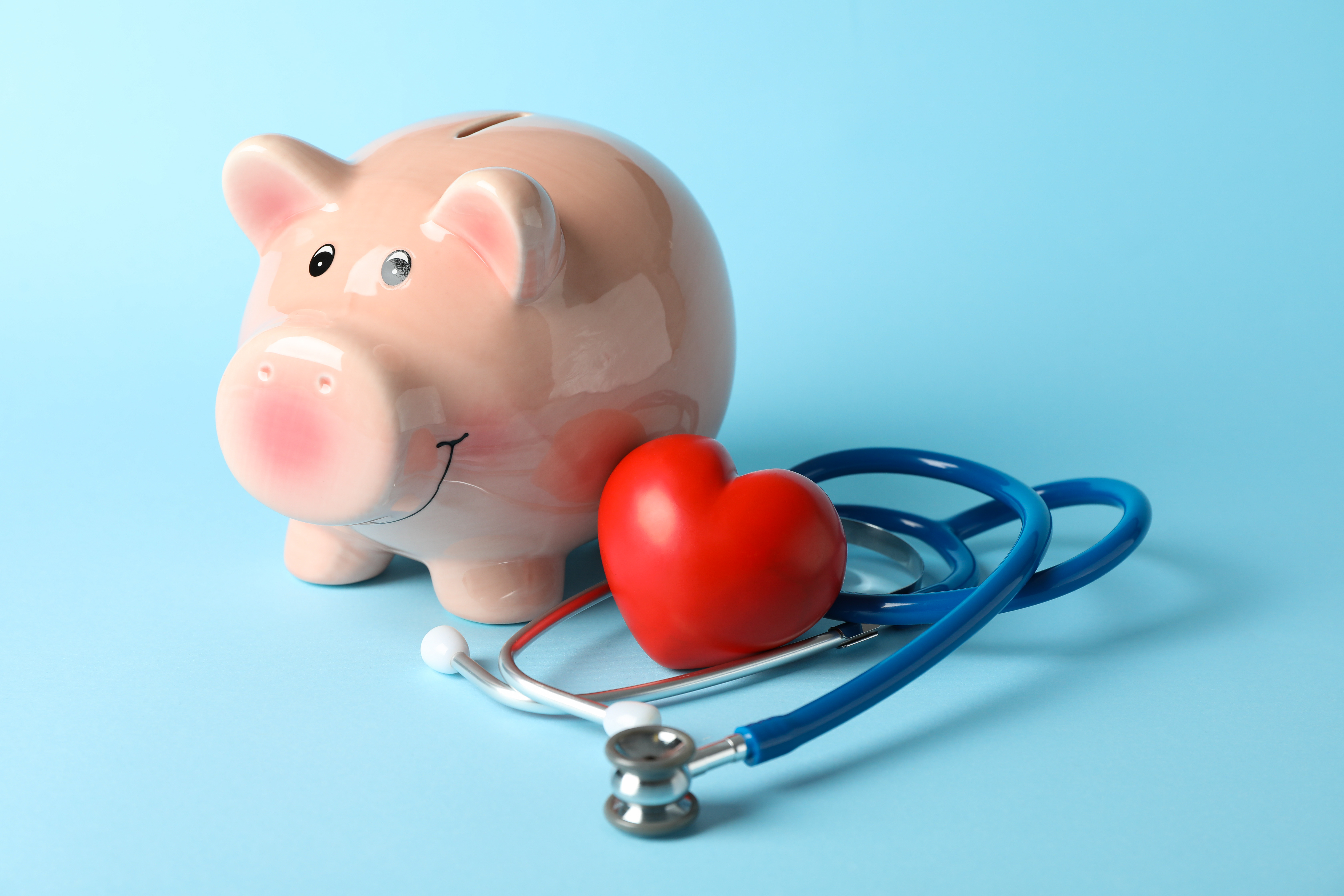  Alcancía acompañada de un corazón y estetoscopio simbolizando la salud financiera