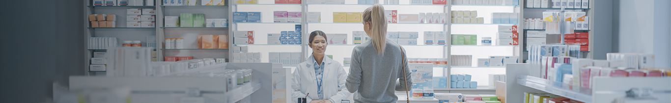 Fotografía de dos personas en el mostrador de una farmacia con descuentos.