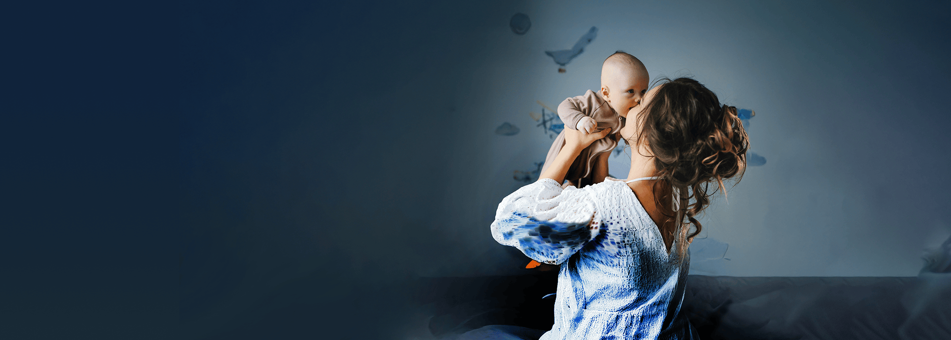 Fotografía de una madre con su bebé en fondo oscuro, con la tranquilidad que entregan los chequeos preventivos de Clínica Alemana.