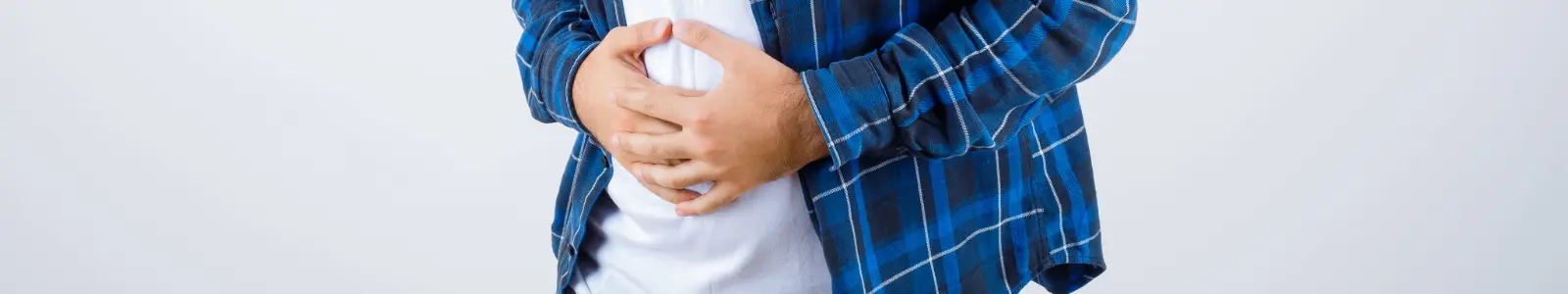 Persona con dolor abdominal y malestar estomacal, síntomas asociados a la gastritis.