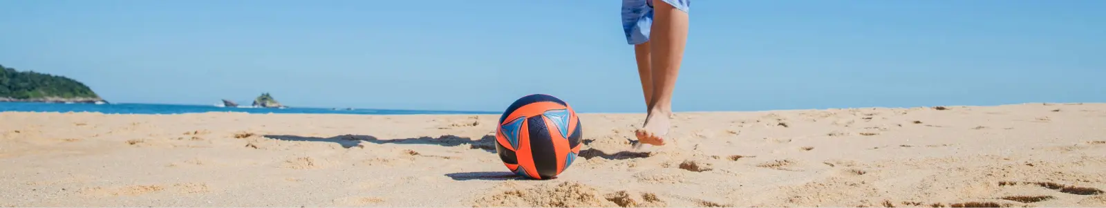 Persona practicando fútbol en la playa, imagen asociada a la protección y coberturas de un seguro de accidentes.