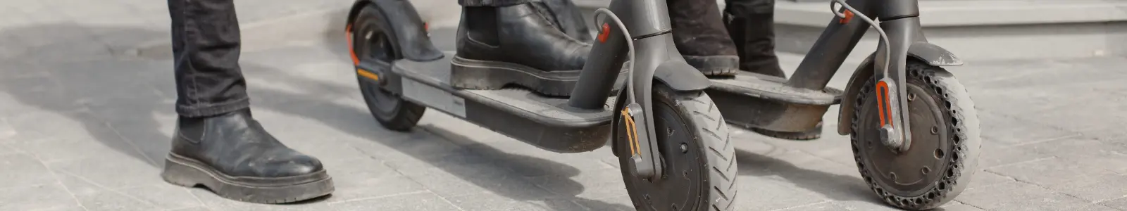 Usuarios de scooter eléctrico en la vía pública, actividad que puede implicar caídas y accidentes sin protección adecuada.