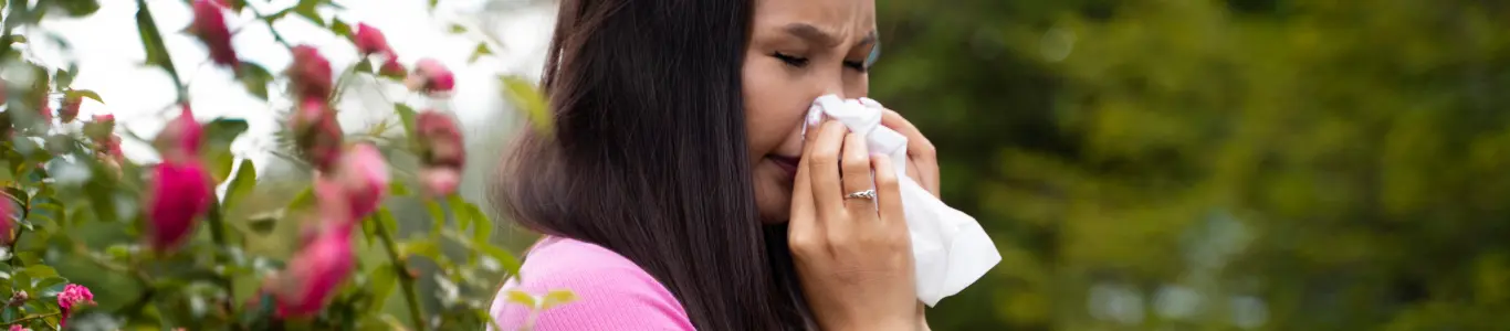 Síntomas de alergia primaveral por polen: estornudo y congestión nasal en exteriores.