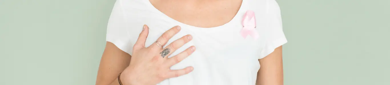 Mujer con camiseta blanca y lazo rosado en el pecho, símbolo de concientización sobre el cáncer de mama.