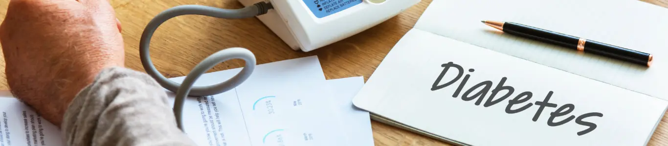 Monitor de salud y cuaderno con la palabra diabetes, ilustrando hábitos y controles para prevenir la diabetes.