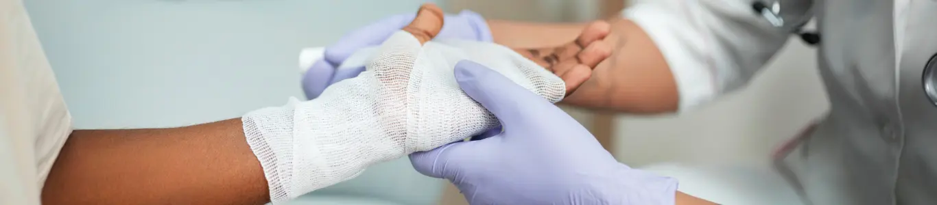 Mano con quemadura siendo cubierta con gasa por personal médico, parte del manejo adecuado de quemaduras.