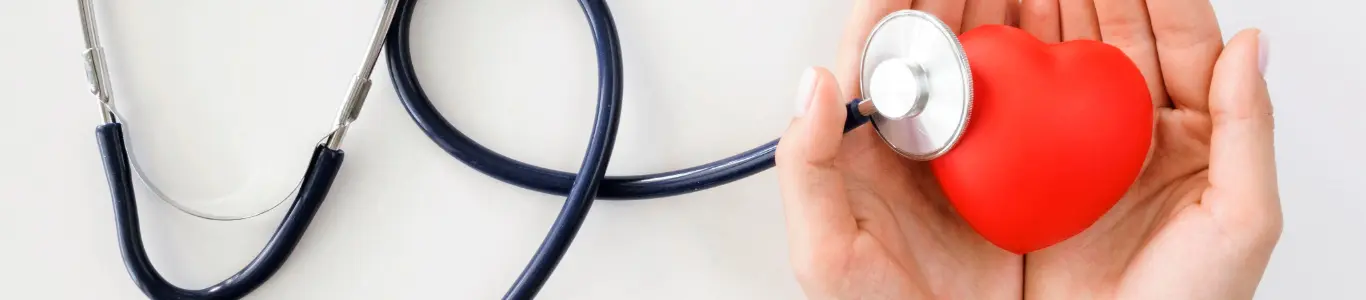Estetoscopio y corazón en manos, símbolo de cuidado médico y prevención en consultas y exámenes de salud.