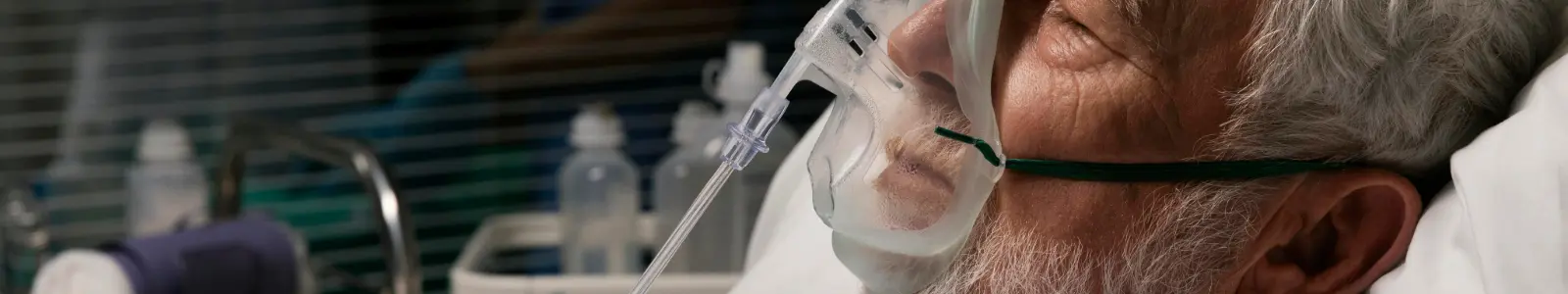 Adulto mayor hospitalizado con mascarilla de oxígeno por neumonía, una enfermedad respiratoria que requiere atención médica oportuna.