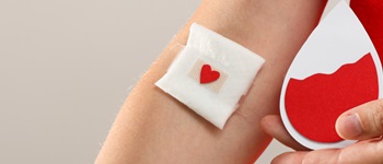 Persona después de donar sangre con una curita en el brazo y una gota simbólica en la mano, representando la importancia de derribar los mitos de donar sangre y promover la solidaridad, en una campaña de Alemana Seguros.