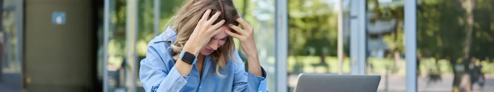 Mujer con signos de estrés y agotamiento frente al computador, imagen relacionada con el impacto del estrés en la salud física y mental.