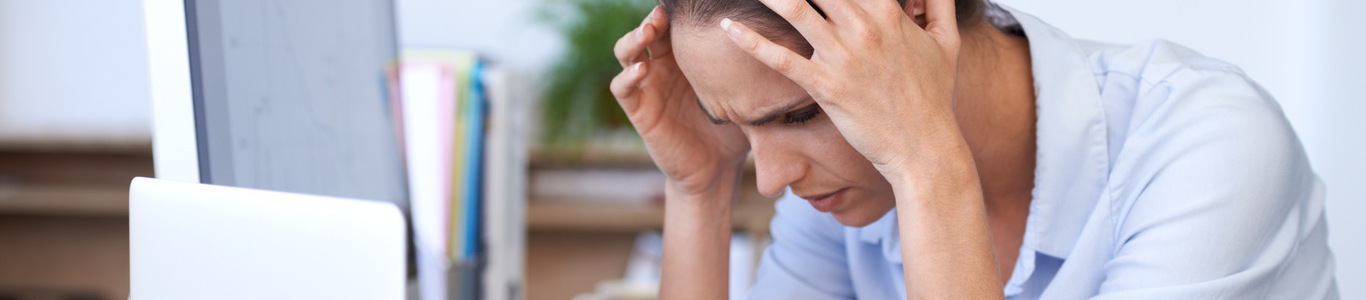 Mujer con signos de burnout frente al computador, destacando la necesidad de un seguro de salud que apoye en situaciones de estrés laboral