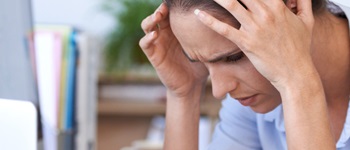 Mujer con signos de burnout frente al computador, destacando la necesidad de un seguro de salud que apoye en situaciones de estrés laboral
