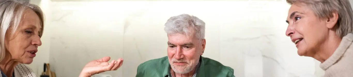 Adulto mayor en conversación con sus cercanos, cuidados preventivos para reducir riesgo de descompensación en verano.